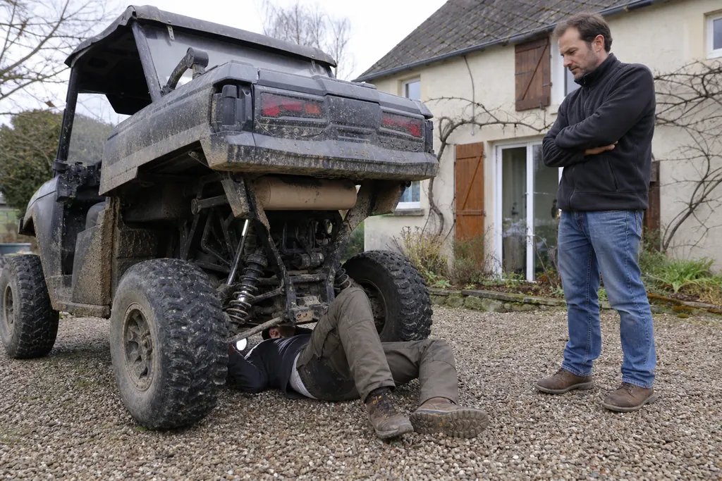 Un acheteur inspecte le dessous d'un SSV d'occasion devant le vendeur