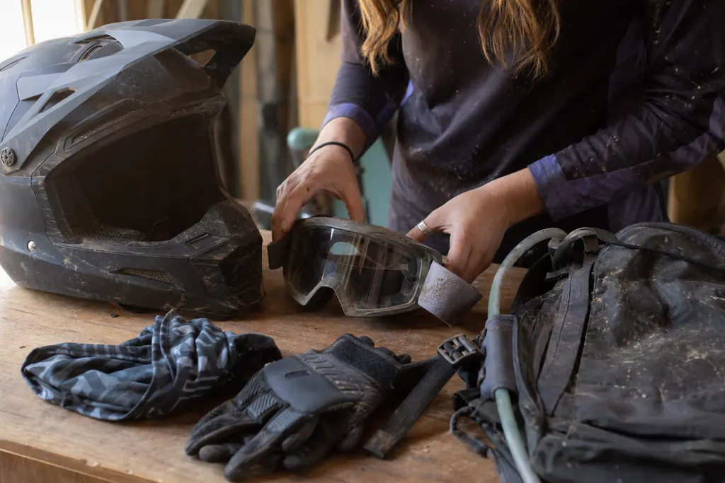 Casque cross, masque, gants et tour de cou posés sur un établi