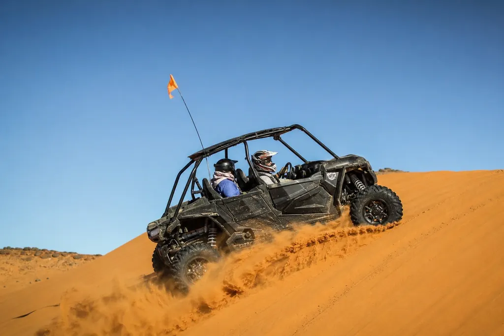 Un SSV équipé d'un fouet gravit une grande dune de sable au Maroc