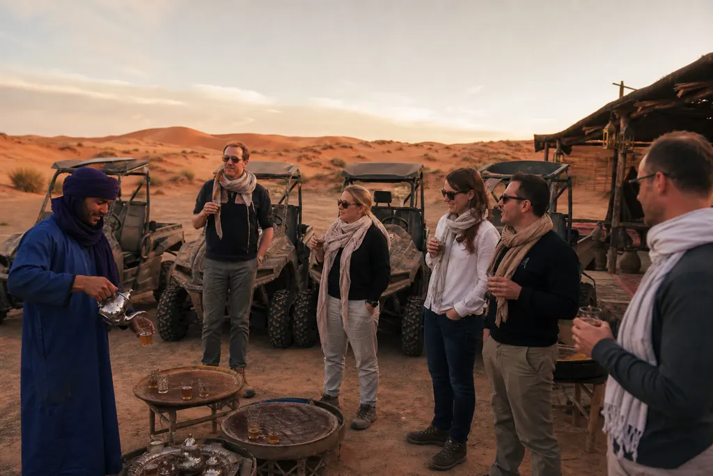 Des voyageurs partagent un thé avec leur guide à côté de leurs SSV dans le désert marocain