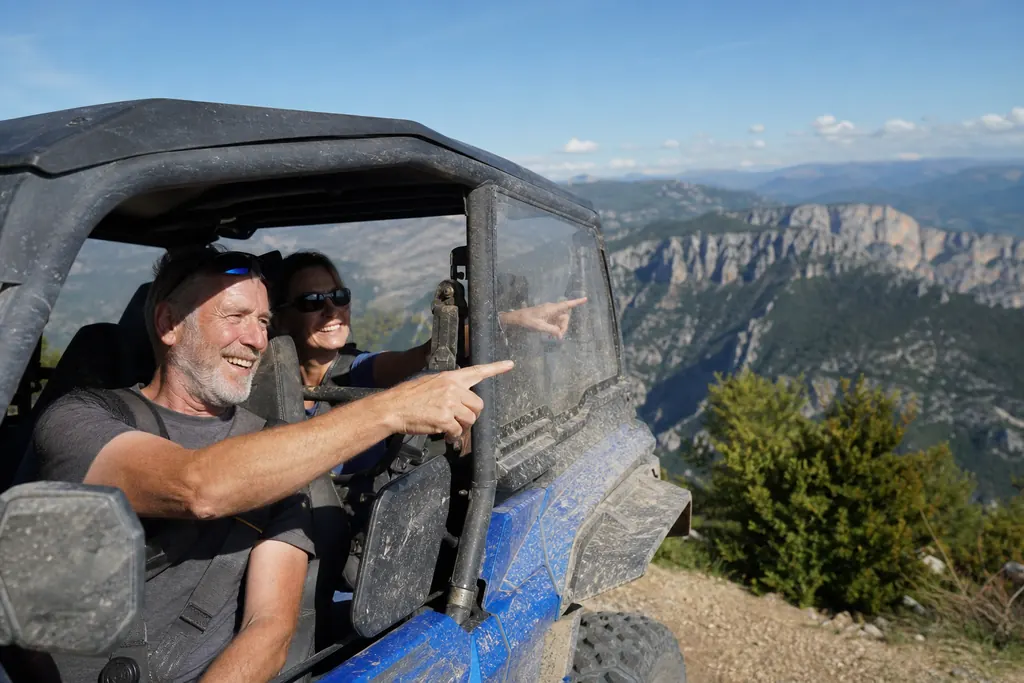 Un couple dans un SSV de loisir bleu admire un canyon depuis un belvédère