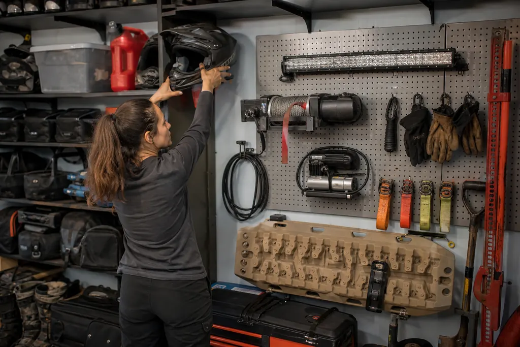 Un mur d'atelier garni d'équipements pour SSV, une femme prend un casque