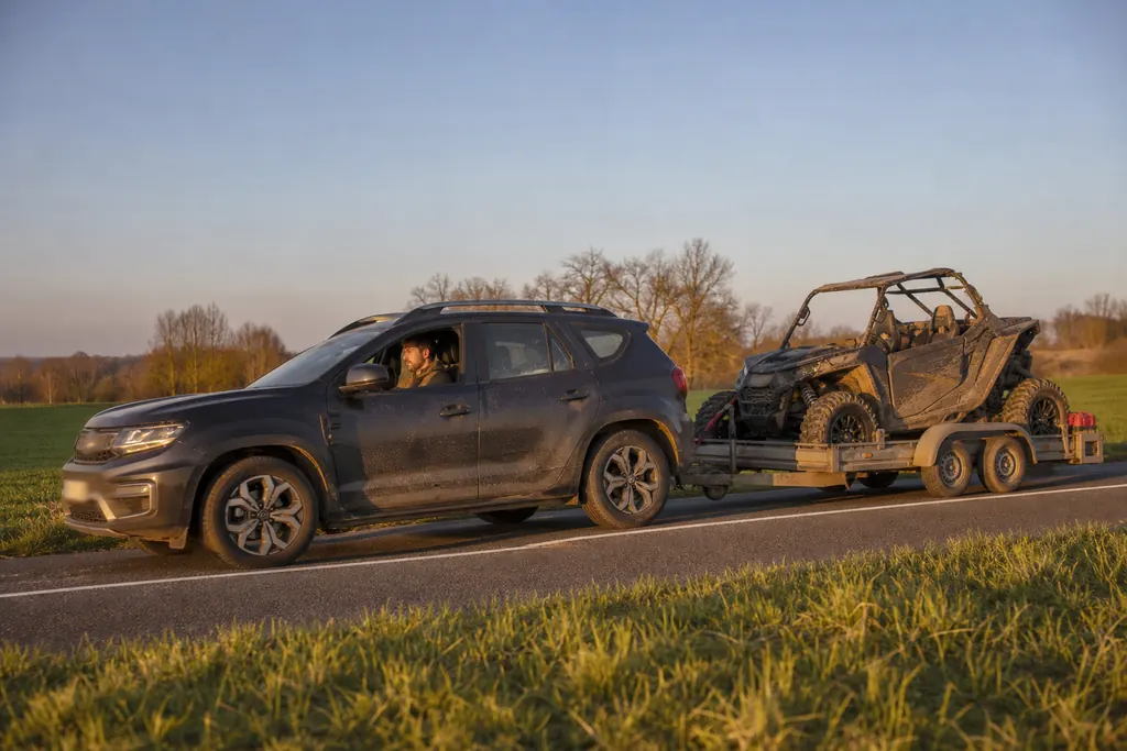 Un SUV tracte une remorque chargée d'un SSV sur une route de campagne