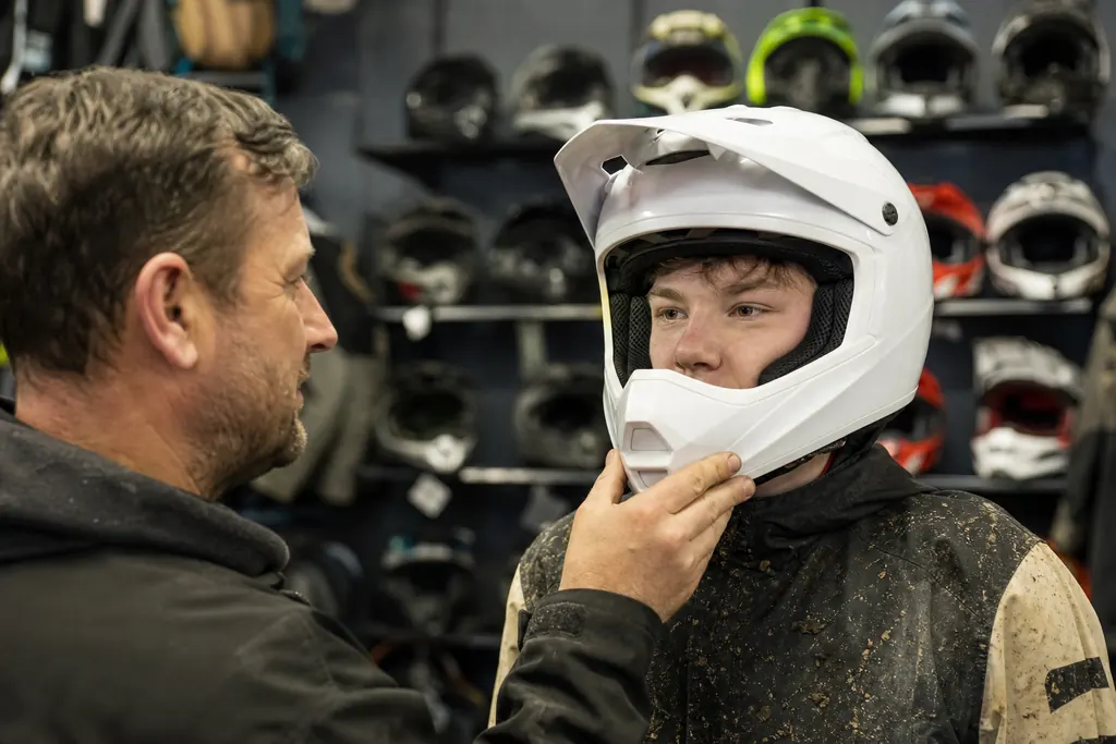 Un adolescent essaie un casque cross en magasin avec son père