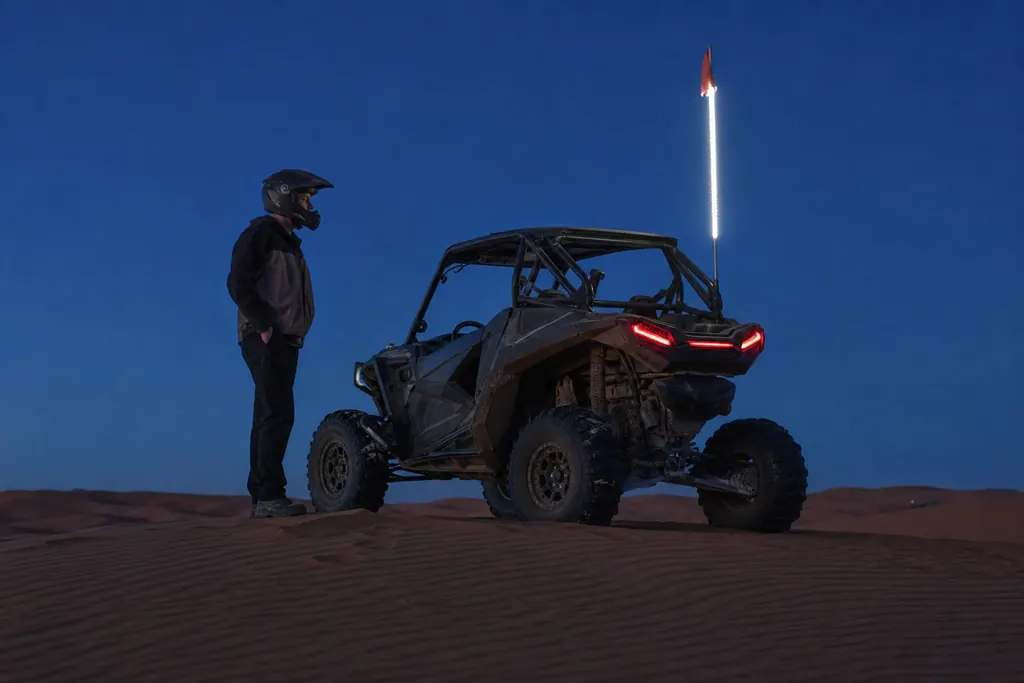 SSV équipé d'un fouet LED allumé au sommet d'une dune au crépuscule