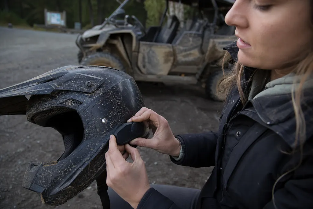 Une pilote fixe un intercom Bluetooth sur le côté de son casque