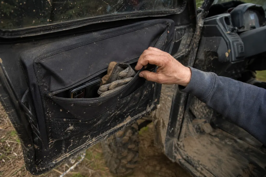 Une main ouvre la sacoche fixée sur la portière d'un SSV