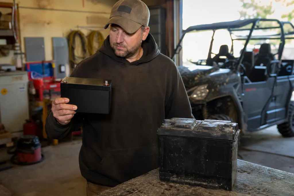 Un homme compare une batterie lithium compacte et une ancienne batterie au plomb