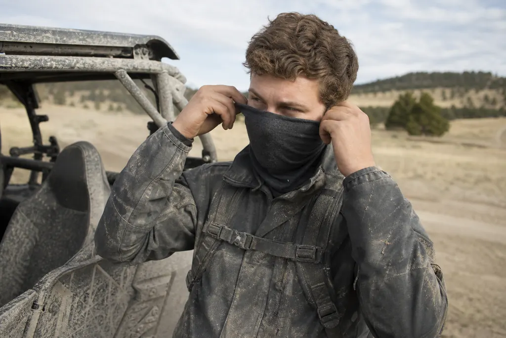 Un jeune homme remonte son tour de cou sur son nez avant de mettre son casque