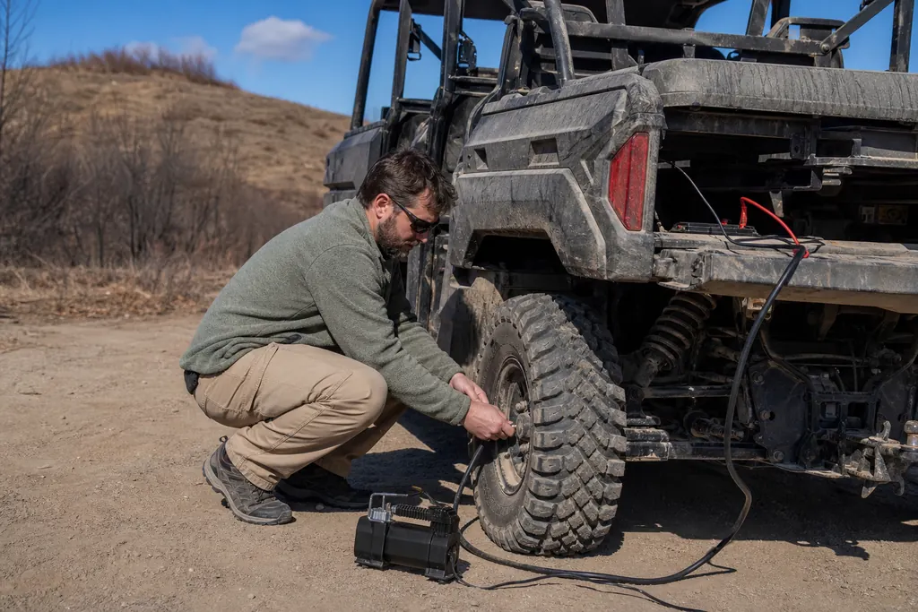 Un homme regonfle le pneu arrière d'un SSV avec un compresseur 12 V portable