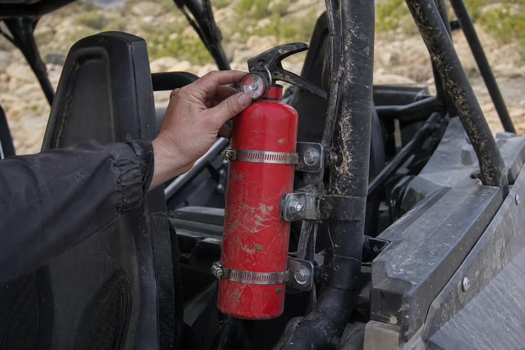Extincteur rouge fixé sur l'arceau d'un SSV, à portée du pilote