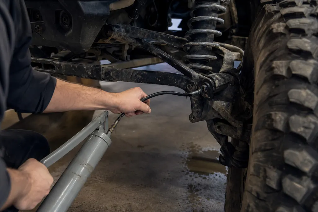 Pompe à graisse raccordée au graisseur d'un bras de suspension de SSV